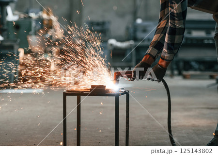 Process of welding. Factory male worker in uniform is indoors Process of welding. Factory male worker in uniform is indoors 125143802
