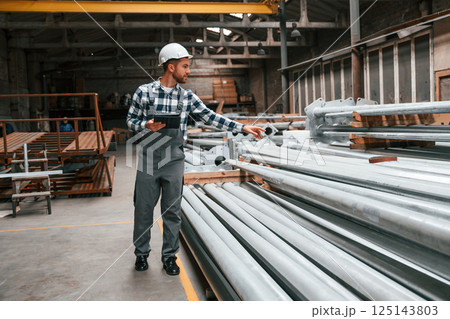 Quality control. Factory male worker in uniform is indoors Quality control. Factory male worker in uniform is indoors 125143803