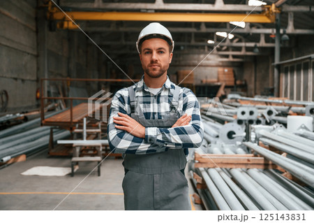 Standing with arms crossed. Factory male worker in uniform is indoors 125143831