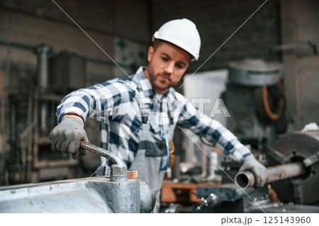 Factory male worker in uniform is indoors. With industry machine 125143960