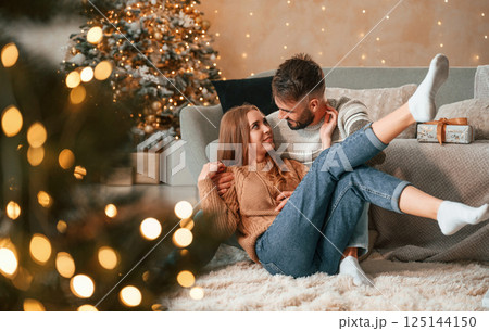 Sitting on the floor together. Lovely young couple are celebrating New Year at home 125144150