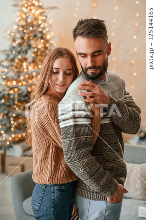 Woman is embracing the man from behind. Lovely young couple are celebrating New Year at home 125144165