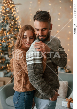 Woman is embracing the man from behind. Lovely young couple are celebrating New Year at home Woman is embracing the man from behind. Lovely young couple are celebrating New Year at home 125144166