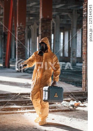 Man dressed in chemical protection suit in the ruins of the post apocalyptic building Man dressed in chemical protection suit in the ruins of the post apocalyptic building 125144345
