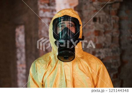 In respirator, portrait. Man dressed in chemical protection suit in the ruins of the post apocalyptic building 125144348