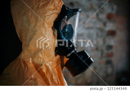 Side view. Man dressed in chemical protection suit in the ruins of the post apocalyptic building Side view. Man dressed in chemical protection suit in the ruins of the post apocalyptic building 125144349