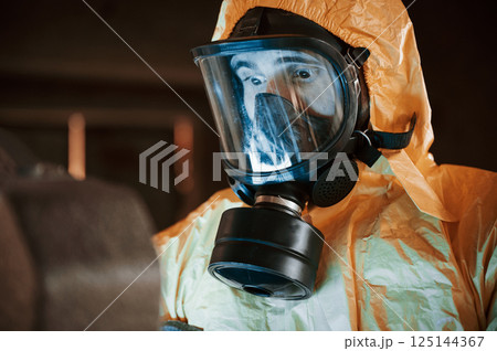 Frightened scientist is with radioactive materials. Man dressed in chemical protection suit in the ruins of the post apocalyptic building Frightened scientist is with radioactive materials. Man dressed in chemical protection suit in the ruins of the post apocalyptic building 125144367