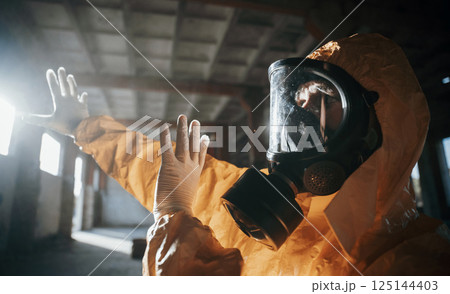 Light from nuclear explosion. Man dressed in chemical protection suit in the ruins of the post apocalyptic building 125144403