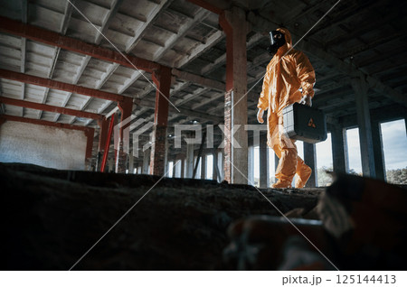 View from below. Man dressed in chemical protection suit in the ruins of the post apocalyptic building View from below. Man dressed in chemical protection suit in the ruins of the post apocalyptic building 125144413