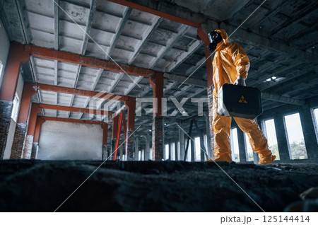 View from below. Man dressed in chemical protection suit in the ruins of the post apocalyptic building 125144414