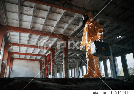 View from below. Man dressed in chemical protection suit in the ruins of the post apocalyptic building View from below. Man dressed in chemical protection suit in the ruins of the post apocalyptic building 125144415