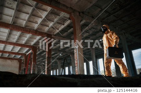 View from below. Man dressed in chemical protection suit in the ruins of the post apocalyptic building 125144416