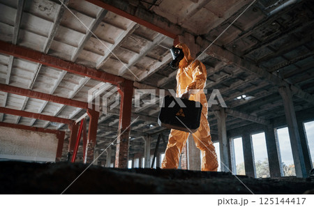 Bottom view. Man dressed in chemical protection suit in the ruins of the post apocalyptic building 125144417