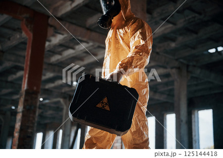Bottom view. Man dressed in chemical protection suit in the ruins of the post apocalyptic building 125144418
