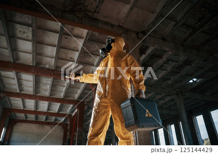Using the flashlight. Man dressed in chemical protection suit in the ruins of the post apocalyptic building Using the flashlight. Man dressed in chemical protection suit in the ruins of the post apocalyptic building 125144429
