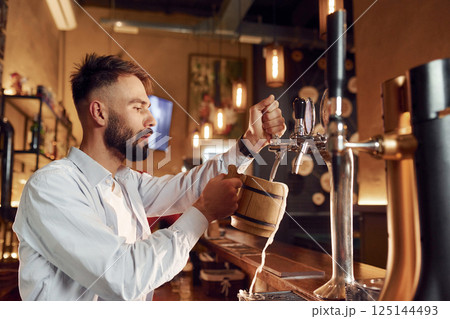 Bartender pours beer. Man is working in the bar 125144493