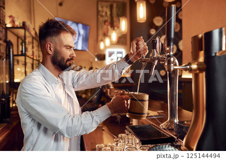 Bartender pours beer. Man is working in the bar 125144494