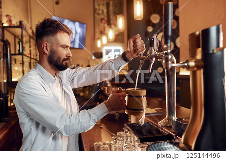 Bartender pours beer. Man is working in the bar 125144496