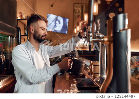 Bartender pours beer. Man is working in the bar 125144497