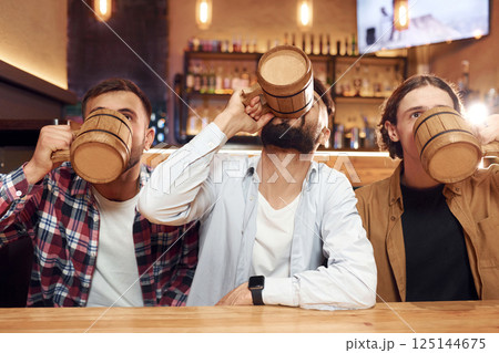 Three friends are in the bar drinking beer and having a good time 125144675