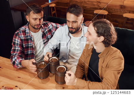 Top view. Sitting by the table. Three friends are in the bar drinking beer and having a good time 125144683