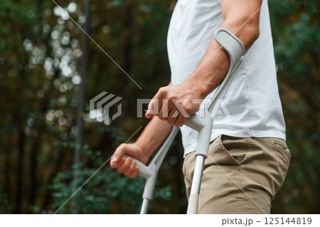 Close up view. Man with crutches is in the park outdoors. Having leg injury 125144819