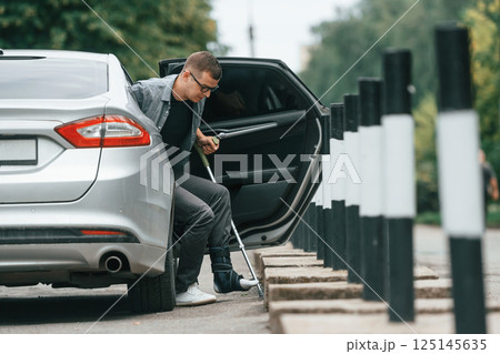 Injured man with crutches is going out from the car 125145635
