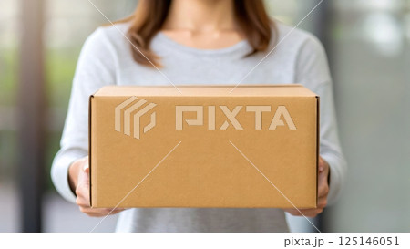 delivery and dropoff concept, Woman holding a cardboard box indoors. 125146051