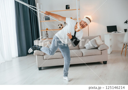Dancing with crutches. Man is at home indoors. Having injuries 125146214