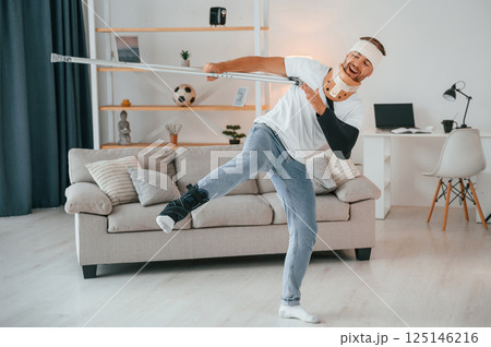 Dancing with crutches. Man is at home indoors. Having injuries Dancing with crutches. Man is at home indoors. Having injuries 125146216