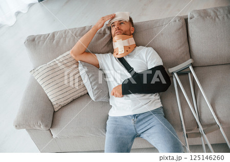 Laying down and suffering from the pain. Man with crutches is at home indoors. Having injuries 125146260