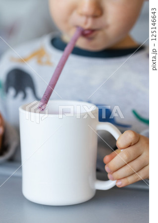 Little child drinking milk shake through a straw. Closeup, selective focus. 125146643