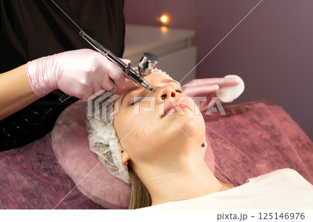 Young woman undergoing facial hydrafacial rejuvenation treatment in spa 125146976