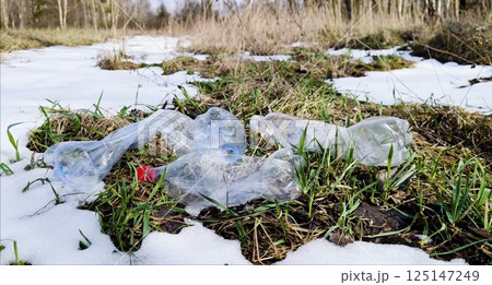 Plastic bottles are like garbage in the snow in spring. There is garbage in the forest in the form of empty plastic bottles after winter, in spring. plastic bottle onto the green grass. Plastic bottles are like garbage in the snow in spring. There is garbage in the forest in the form of empty plastic bottles after winter, in spring. plastic bottle onto the green grass. 125147249