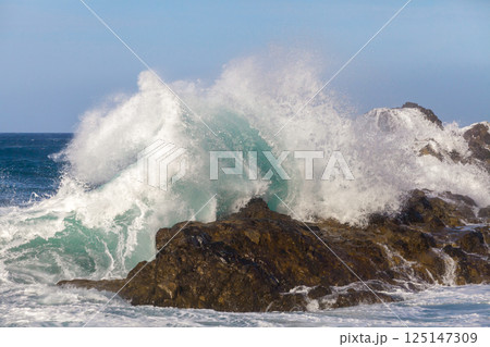 Ocean waves crushing against rocks 125147309