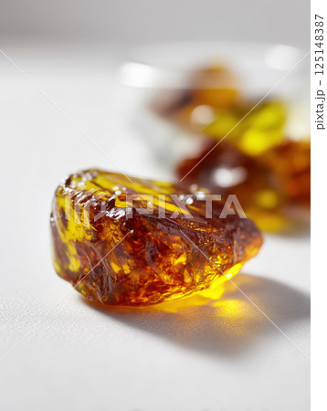 Ultra-realistic macro close-up of multiple natural amber stones with unique textures on white background under studio lighting. High quality photo 125148387