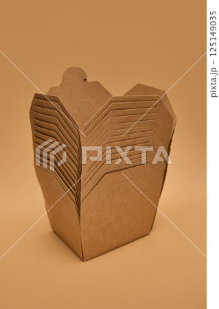 Stacked kraft paper food boxes against light brown background. Concept of packaging, delivery, recycling, eco materials. Stacked kraft paper food boxes against light brown background. Concept of packaging, delivery, recycling, eco materials. 125149035