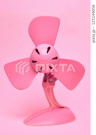Monochromatic bright pink electric fan against textured light pink background. Cooling and vibrant aesthetic. Air conditioning, fan products. 125149056