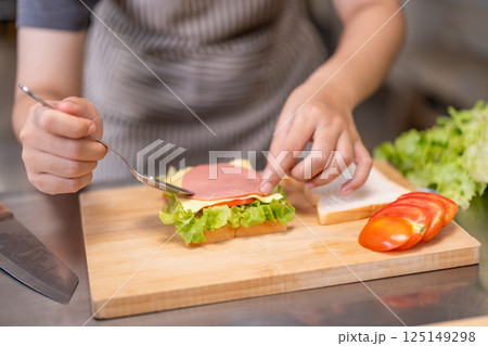 Smiling Young Female Chef Preparing a Sandwich in a Professional Kitchen 125149298