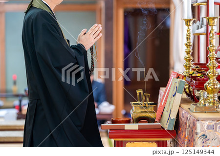 祭壇前で祈る僧侶 125149344