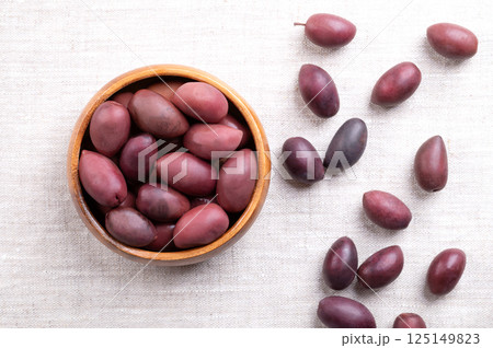 Kalamata olives with pit, in wooden bowl on linen. Hand-picked large, purple olives, with smooth, meaty texture, named after Greek city Kalamata. Preserved in wine vinegar. Also called Kalamon olives. Kalamata olives with pit, in wooden bowl on linen. Hand-picked large, purple olives, with smooth, meaty texture, named after Greek city Kalamata. Preserved in wine vinegar. Also called Kalamon olives. 125149823