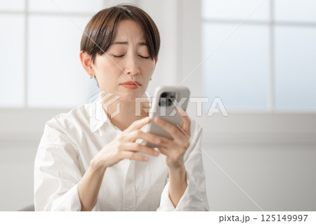 スマホを見て困った顔の女性 スマホを見て困った顔の女性 125149997