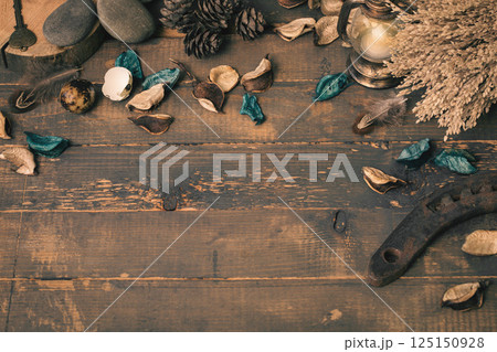 Witchcraft atmospheric flat lay. Dry herbs, blue flower petals, stones, small lantern, old horseshoe, birds feather on rude wooden surface, copy space. 125150928