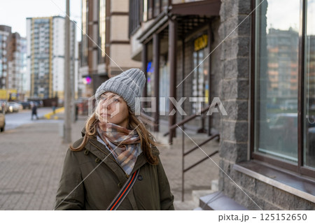 Portrait of mature woman in wool hat standing on the urban street, drinking takeaway coffee from paper cup. Middle-aged 40s female walking around the city at cold autumn day. Living in modern district Portrait of mature woman in wool hat standing on the urban street, drinking takeaway coffee from paper cup. Middle-aged 40s female walking around the city at cold autumn day. Living in modern district 125152650
