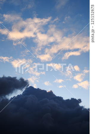 Vertical photograph of blue clouds in overcast weather at sunset. Aesthetically pleasing neutral photograph. Smoke.  125152678