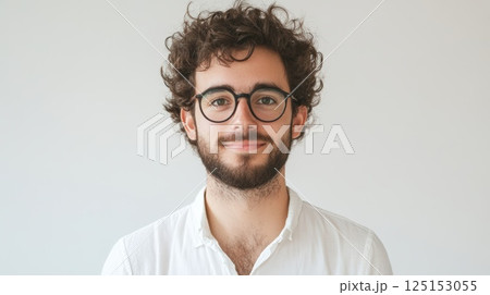 Young Man Smiling With Curly Hair and Round Glasses, Bright Background Young Man Smiling With Curly Hair and Round Glasses, Bright Background 125153055