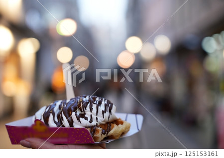 Hand Holding Belgian Waffle with Cream and Chocolate 125153161