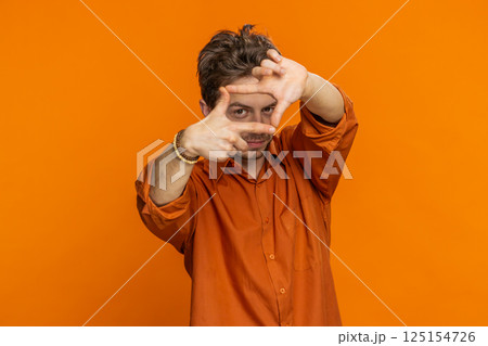 Man photographer gesturing picture frame with hands, looks through fingers focusing cropping image 125154726