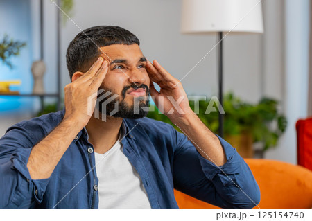 Sick ill Indian man rubbing temples to cure headache problem suffering from tension migraine stress Sick ill Indian man rubbing temples to cure headache problem suffering from tension migraine stress 125154740