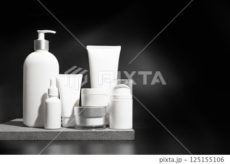 Cosmetic products containers on stone podium and black background Cosmetic products containers on stone podium and black background 125155106